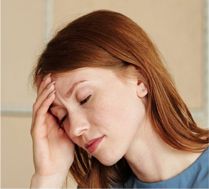 woman holding her forehead while experiencing a headache